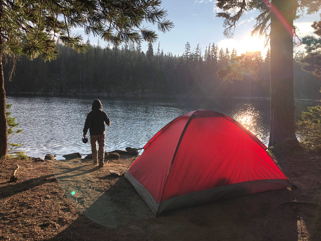 Man with red tent by lake