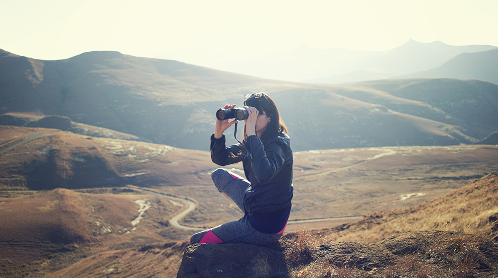 Woman looking through binoculars in wilderness